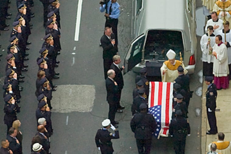 Cardinal Justin Rigali blesses the flag-draped casket of Officer Isabel Nazario (Clem Murray / Inquirer)