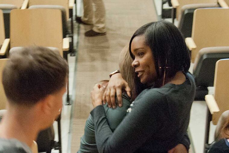 Nicole Brown hugs students of Kensington Creative and Performing Arts High School, after a memorial service Dec. 18, 2013 for a former student who was murdered over the weekend. Brown, who was laid off from her job as a counselor at the school back in the summer, came back to support her former students. With the drastic budget cuts in the Philadelphia School District, principals and teachers are forced to do more, and different things, to support their students. ( CLEM MURRAY / Staff Photographer )