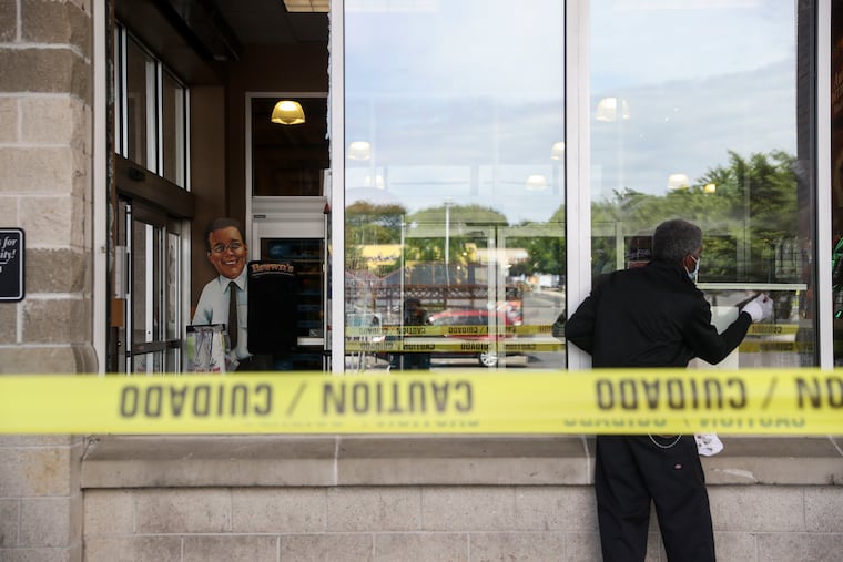 A cardboard cutout of Jeff Brown is seen through the broken window of the ShopRite on Fox Street in Philadelphia on Monday.