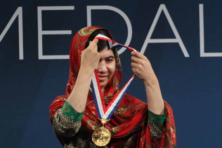 Liberty Medal recipient Malala Yousafzai puts the Liberty medal over her own head after accepting it from NCC President Jeffery Rosen Tuesday night. At the National Constitution Center, Mayor Nutter will recognize Malala Yousafzai, the recipient of the 2014 Liberty Medal, which is awarded annually to a person of courage and conviction who strives to secure the blessings of liberty to people around the globe. National Constitution Center President, Jeffery Rosen, will present Malala Yousafzai with the Liberty Medal. 10/21/2014 ( MICHAEL BRYANT / Staff Photographer )