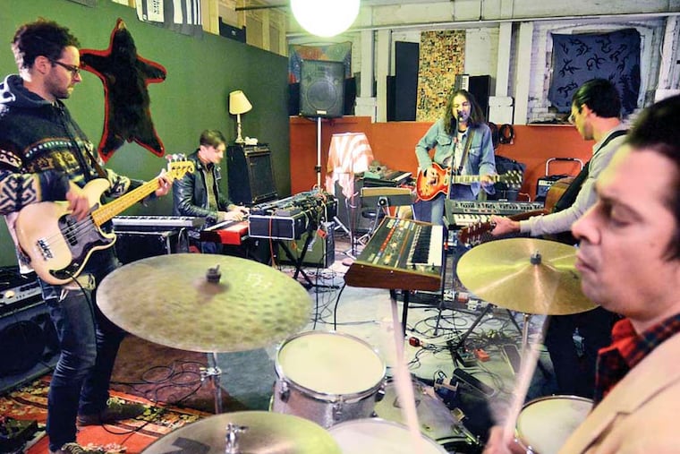 Adam Granciel and The War on Drugs pose at their practice space in Kensington February 25, 2014. Clockwise from left are: Dave Hartley (bass); Robbie Bennett (keyboards); Adam Granduciel (vocals, guitar); Anthony Lamarca (guitar); and Charlie Hall (drums). ( TOM GRALISH / Staff Photographer )