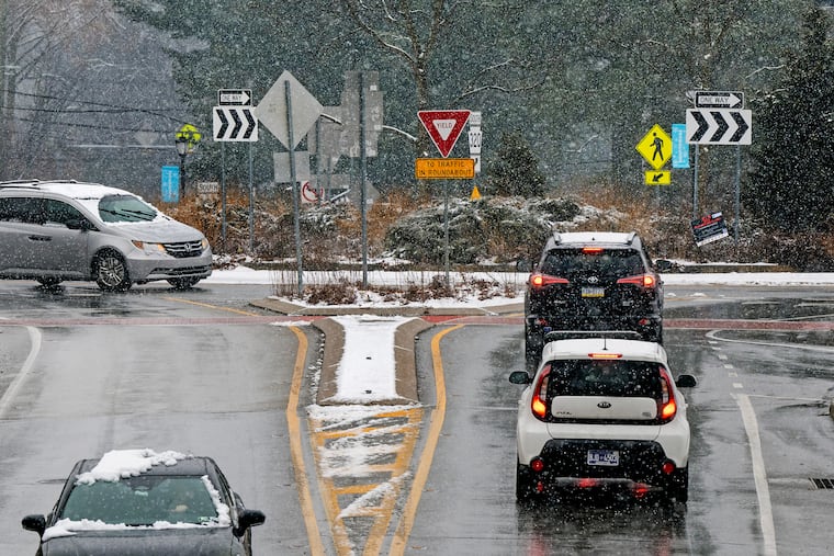 Snow-covered cars drive into and out of the traffic circle on Chester Road in Swarthmore on Sunday during the weekend's second snowfall.