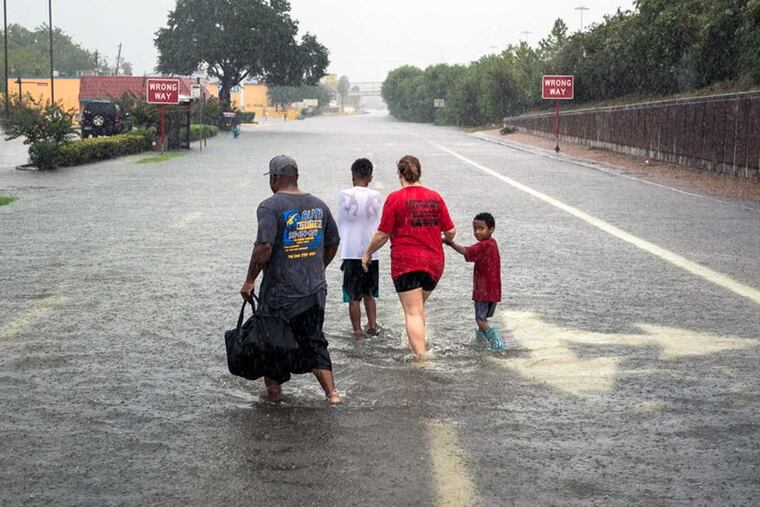 People walk through floodwater near Interstate 10 in Houston on Sunday. Rising water from Hurricane Harvey pushed thousands of people to rooftops and other higher ground.