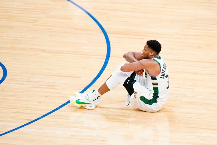 Milwaukee's Giannis Antetokounmpo sits on the court after putting the Sixers away during overtime Wednesday at Wells Fargo Center.
