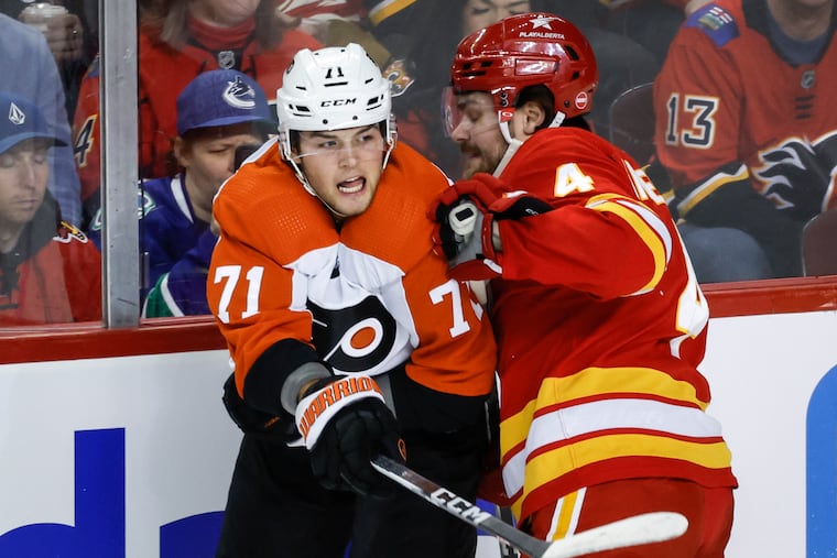 Philadelphia Flyers forward Tyson Foerster, left, is checked by Calgary Flames defenseman Rasmus Andersson, right, during first-period NHL hockey game action in Calgary, Alberta, Sunday, Dec. 31, 2023. (Jeff McIntosh/The Canadian Press via AP)