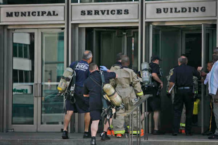Members of the Fire Department's Hazmat unit respond after beige powder spilled from an envelope in a room where workers open water-bill payments.