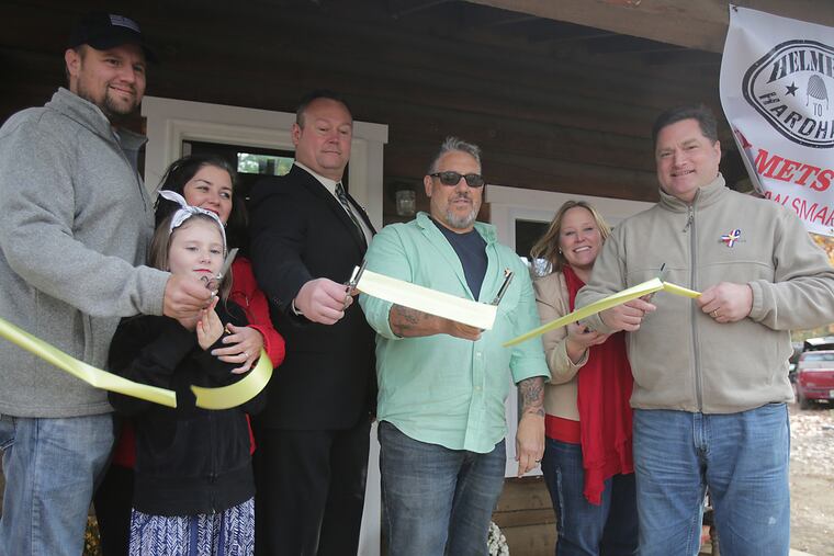 A ribbon-cutting ceremony in held in front of a refurbished cabin. From left, Pastor, Donnie Davis from Amazing Grace ministry: his daughter Sophia Davis, 10; his wife Jennifer Davis; Bryan Bush from Sheet Metal Workers Local Union 19; Anthony Raymond -- Director of Operation Safe Haven; Tammy Koller and her husband Ron Koller who is from Sheet Metal Workers Local Union 19.
