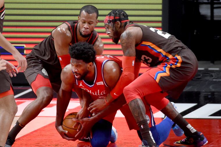 Sixers center Joel Embiid, center, scrambles for the ball against Portland Trail Blazers guard Rodney Hood, left, and forward Robert Covington during the first half.