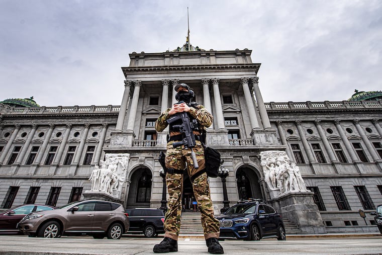A member of the Pennsylvania Capitol Police stands guard at the entrance to the Pennsylvania Capitol Complex in Harrisburg, Pa., Wednesday, Jan. 13, 2021. State capitols across the country are under heightened security after the siege of the U.S. Capitol last week.