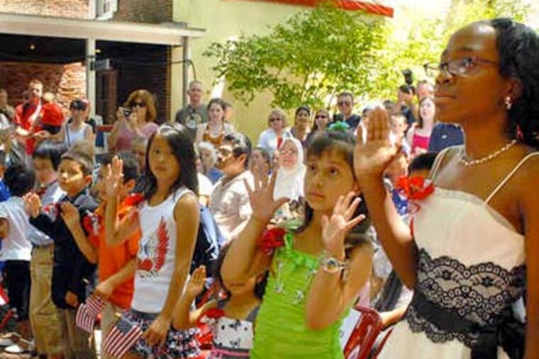 A daughter of Cameroonian parents, Melissa Menkeng (right), 11, raises a hand while Estrella Lopez Mejia, 7, whose family is from Peru, lifts both. Melissa, who lives in Upper Darby, said the Independence Day ceremony meant "that I'm an American, and I'm responsible." Estrella lives in Jonestown, Pa. (Tom Gralish / Staff Photographer)