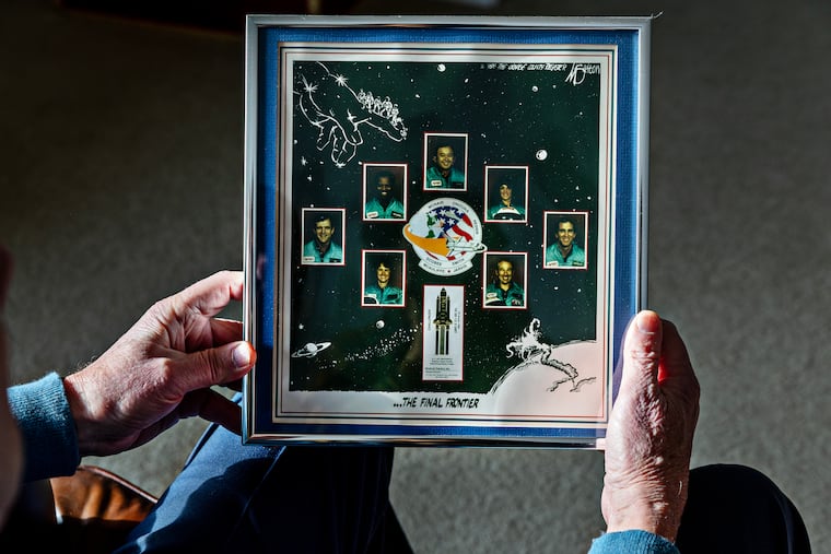 Brian Russell holds a picture that hangs on a wall at his home that memorializes the astronauts killed in the Challenger explosion.