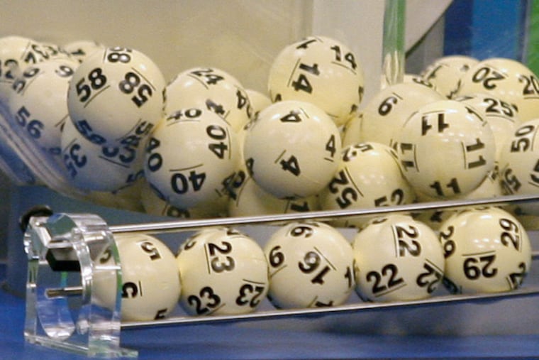 The five balls at the bottom helped two tickets win a $587.5 million jackpot in the Nov. 28, 2012, Powerball drawing. At the time, it was the game's biggest prize ever. The red Powerball is selected separately. (Phil Sears / Associated Press)