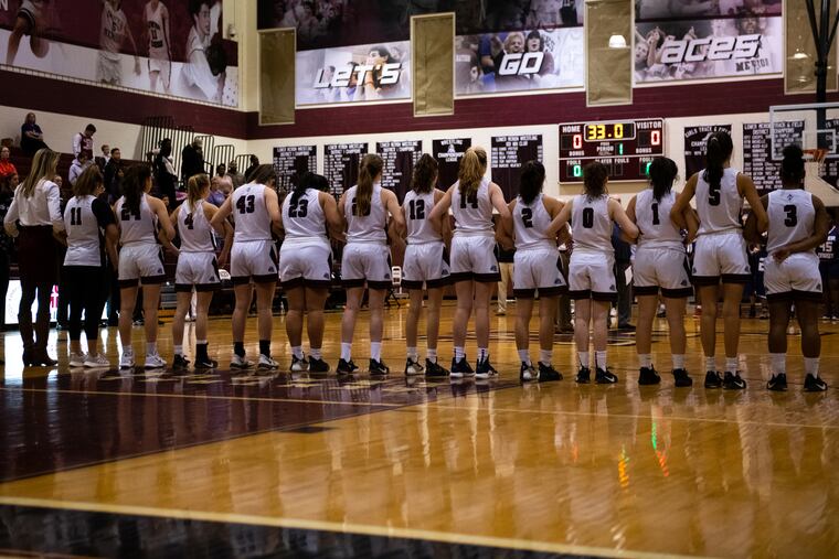 The Lower Merion girls' basketball team links arms before a 33-second moment of silence for Kobe Bryant before their game against Upper Darby.