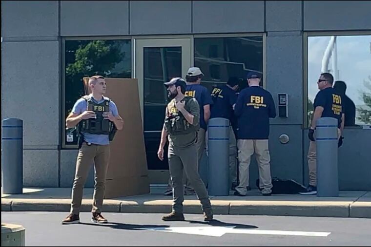 In this image taken from FOX19 Cincinnati video, FBI officials gather outside the FBI building in Cincinnati, Thursday, after an armed man decked out in body armor tried to breach a security screening area at the FBI field office in Ohio then fled and exchanged gunfire in a standoff with law enforcement, authorities said.