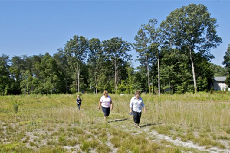 Neighbors, left to right, Alave Phifer, Mary Palumbi and Lisa Cowne walking along a trail in the proposed site of a $21 M, 11-acre army reserve training facility in Gloucester Township. ( John Costello / Staff Photographer )