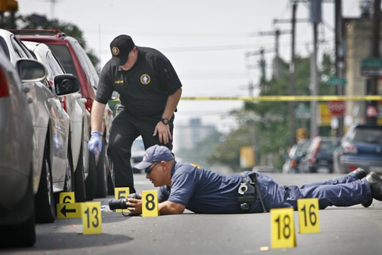 Philadelphia police crime scene unit workers gather evidence from the shooting scene around South 21st Street at Titan Street near Wharton Street in South Philadelphia on Thursday morning.