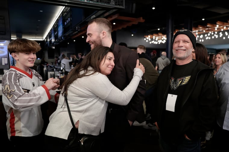 Jen Mix hugs Wings defender Alex Pace as her husband Tom Mix (right) looks on. Tom Mix received a bone marrow transfer from Pace in 2021.