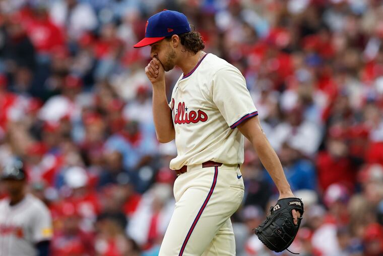 Aaron Nola blows into his hand after giving-up a two run first inning home run to Braves' Ozzie Albies on March 30.