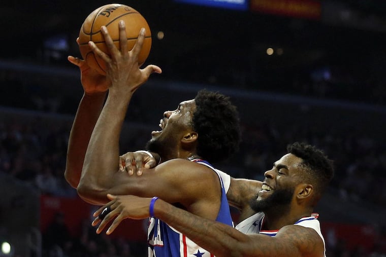 The Clippers' Willie Reed, right, fouls the 76ers' Joel Embiid on Monday night.