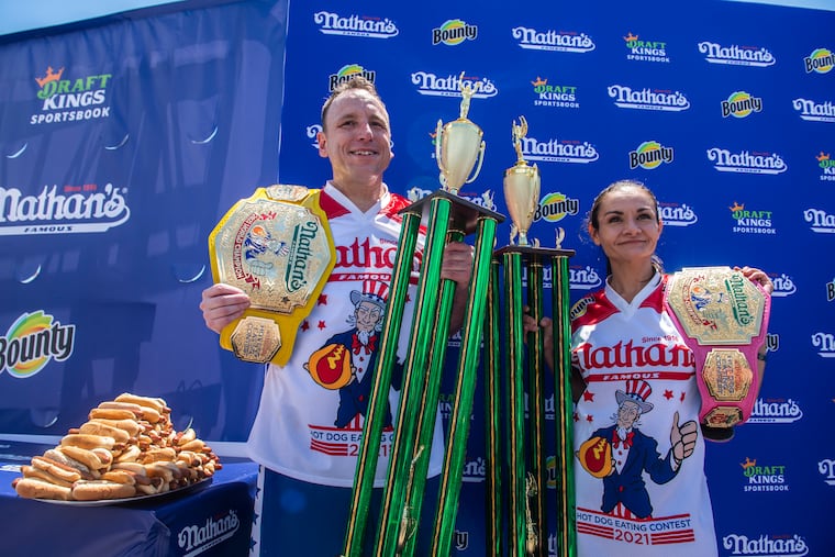 Winners Joey Chestnut and Michelle Lesco pose with their championship belts and trophies at the Nathan's Famous Fourth of July International Hot Dog-Eating Contest in Coney Island's Maimonides Park on Sunday, July 4, 2021, in Brooklyn, New York.