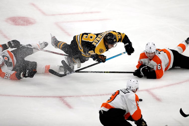 Boston Bruins right wing David Pastrnak (88) goes down as he chases the puck against Philadelphia Flyers center Claude Giroux (28) and defenseman Travis Sanheim (6) in the third period of an NHL hockey game, Thursday, Jan. 31, 2019, in Boston. (AP Photo/Elise Amendola)