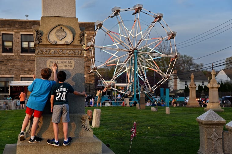 Tom Forrester (left) and Andrew Otten play hide and seek in the St. Denis Church cemetery with Victoria Laabs, who remains hidden, while attending the church’s Family Fun Fair May 2, 2018. A throwback in parochial Havertown, the Catholic fair is open for its 50th year.