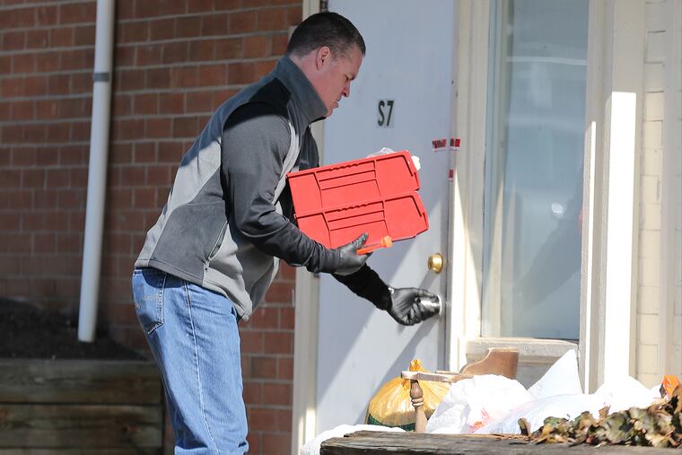 An investigator enters the crime scene at the Robert Morris Apartments in Morrisville after five relatives were found dead inside.