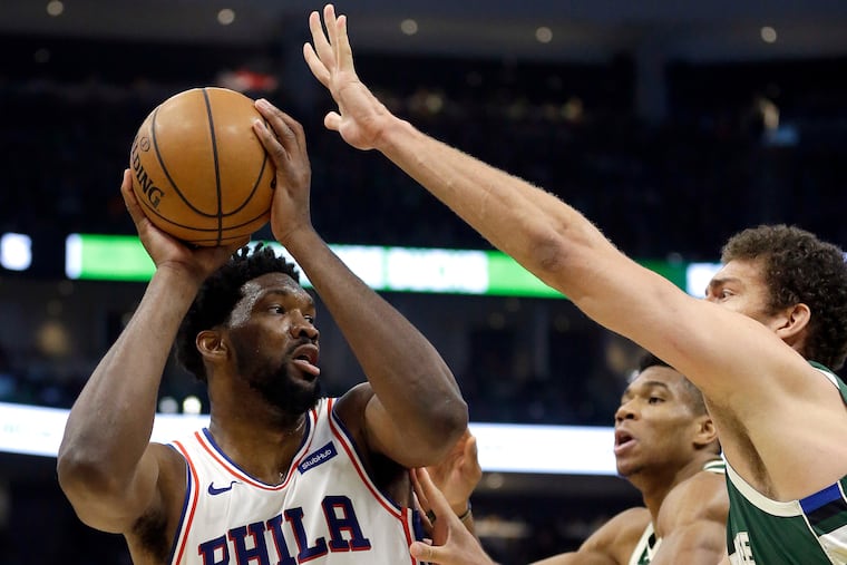 Joel Embiid tries to put a shot over the Bucks' Brook Lopez (right) and Giannis Antetokounmpo during the first half of the Sixers' win on Sunday.