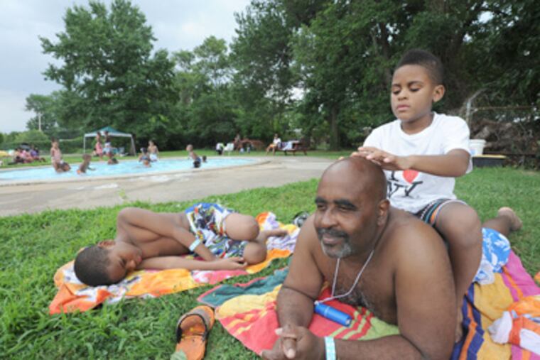 Relaxing, James Robb and grandsons Kamil Garrett (left), 8, and Caleb Garrett, 6, enjoy the Nile Swim Club. (April Saul/Staff)