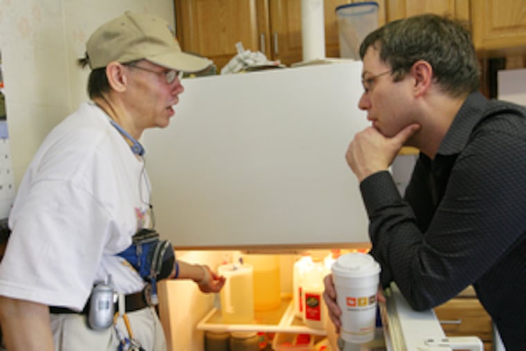 Russell Kidd ( left) and Robert Slack (right), a caseworker with the ARC (Association for Retarded Citizens) of Philadelphia, discuss the best way to reorganize the refrigerator in Kidd's Olney home.