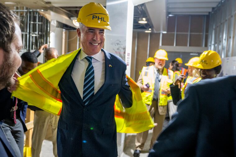 Sen. Bob Casey takes off his safety-wear after he and other elected officials and airport workers viewed construction on the new restroom.