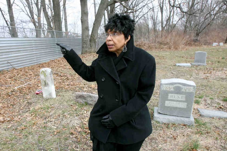 Mina Cockroft of Friends of Eden Cemetery points to a fence meant to stop vandals. Supporters hope fund-raising will advance revitalization.