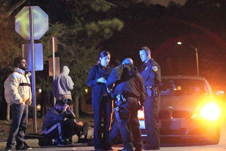Police officers stand outside the condominium complex in Chapel Hill, N.C., where a resident is charged with killing a young husband, wife, and her sister on Tuesday. AL DRAGO / (Raleigh) News & Observer