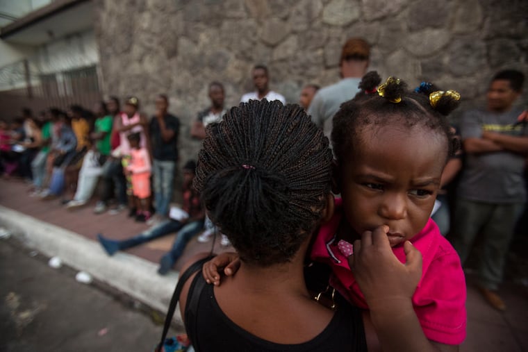 A Haitian woman carries her daughter as she waits outside the Mexican Commission for Migrant Assistance office to get the documents needed that allow them to stay in Mexico, in Tapachula, early Thursday, June 20, 2019.