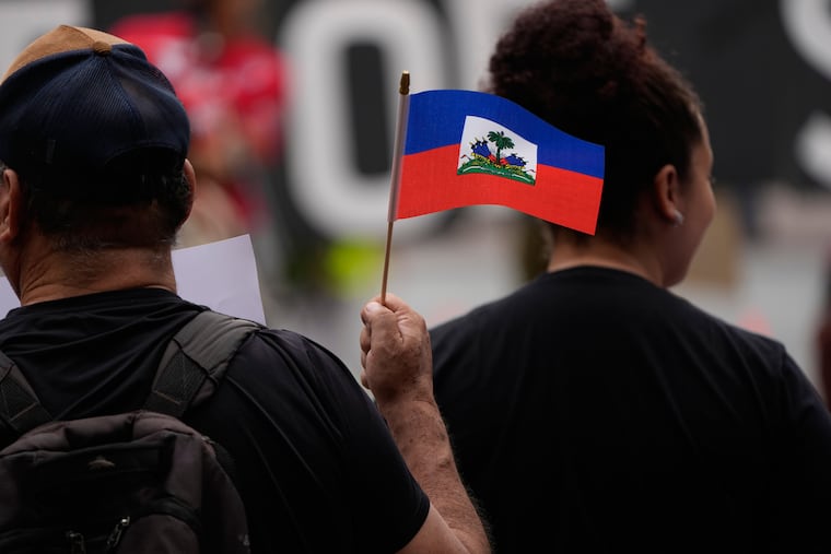 People hold Haitian flags and signs during a rally in support of immigrants living in the United States with temporary protected status, or TPS, Thursday, July 9, 2026, in San Diego. Attorneys for some Haitian immigrants say ICE has begun putting ankle monitors on their clients.
