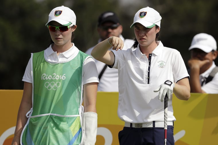 Leona Maguire, right, of Ireland, next to her twin and caddie, Lisa, preparing to hit during the women's golf event at the 2016 Summer Olympics in Rio de Janeiro, Brazil.
