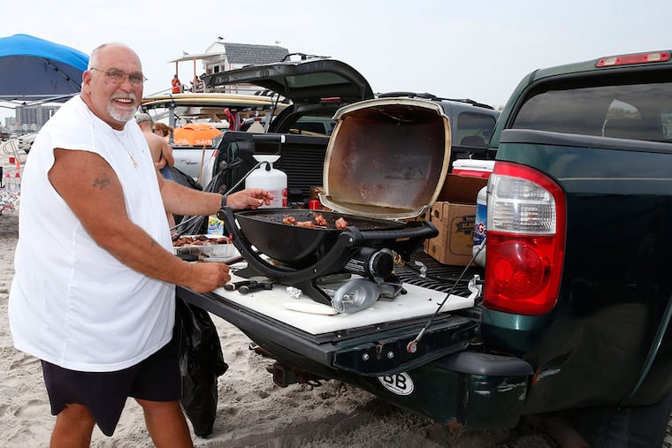 Rich Hill, a meat shop owner from West Chester, grills lunch on the Brigantine Beach. (TOM BRIGLIA/For The Inquirer)