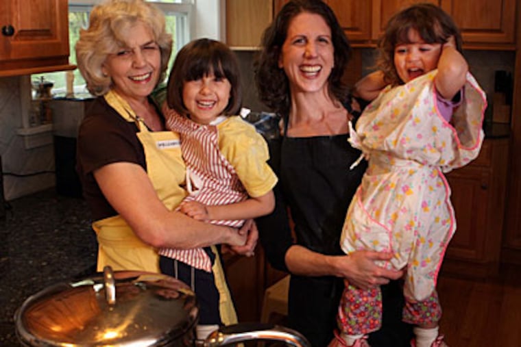 Judy DeHaven (right) with her mother, Pat, and daughters Lillian Woolley and Mae Woolley, 2, in Pat’s Berwyn kitchen. Pat DeHaven learned the art of cooking from a generation of Italians who mixed ingredients by hand until the “feel” was right. (LAURENCE KESTERSON / Staff Photographer)