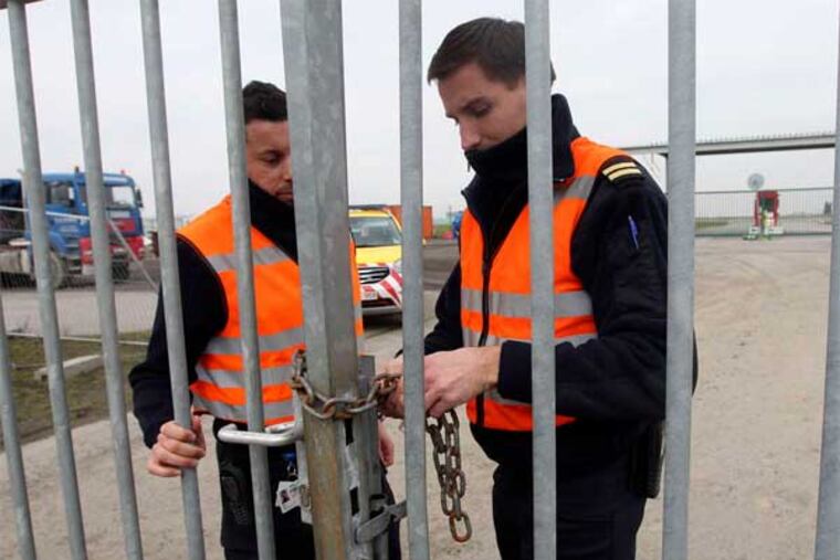 Police officers lock a gate that leads to a Brussels airport tarmac. Robbers made a holein a fence there to snatch $50 million worth of diamonds from a Swiss-bound plane. (Associated Press)