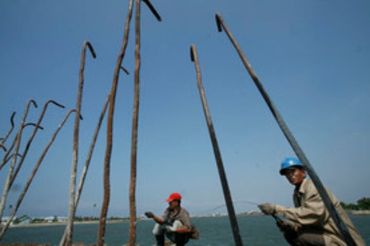 Acehnese men work on a bridge that is to form part of a new road system in Banda Aceh, Indonesia. "When the United Nations and the aid groups leave," said the head of Aceh province's investment board, "we have to be ready with new livelihoods."