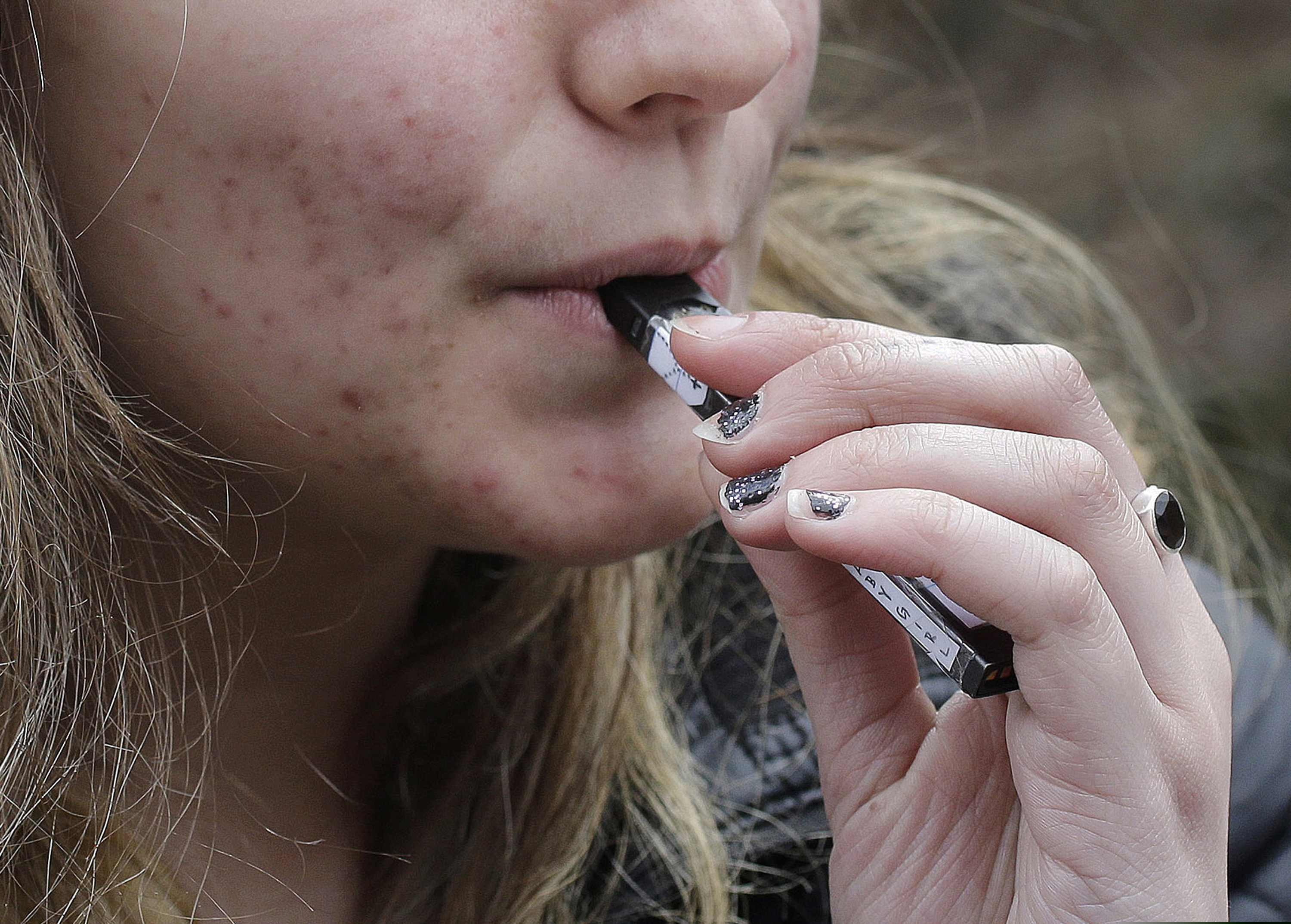 A high school student uses a vaping device near a school campus in Cambridge, Mass. on April 11, 2018. Massachusetts Gov. Charlie Baker declared a public health emergency Sept. 24, 2019, ordering a four-month temporary ban on all vaping products in the state.