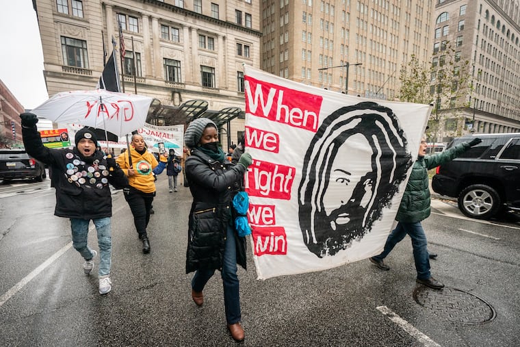 Supporters of Mumia Abu-Jamal march down JFK Blvd. past the Juanita Kidd Stout Center for Criminal Justice and City Hall, in Philadelphia, Friday, December 16, 2022.