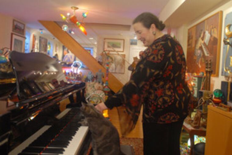 Betsy Alexander, owner of Nora, the piano-playing cat, in her Center City studio. Nora plays along with Alexander's students in their lessons.