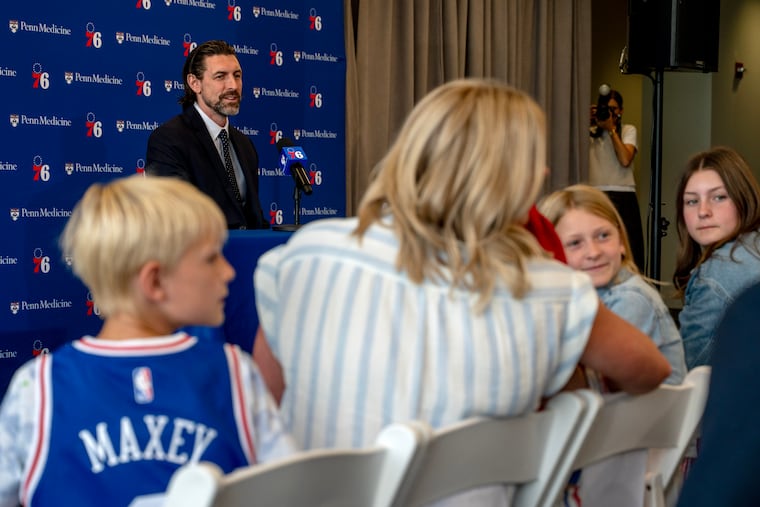 Mike Gansey speaks to the press as his wife, Amy, and their four children look on from the crowd.