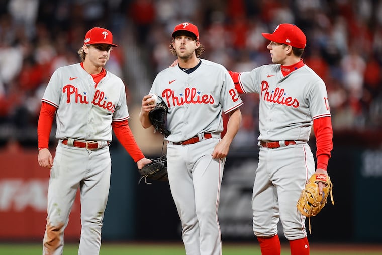 Phillies pitcher Aaron Nola with Bryson Stott (left) and Rhys Hoskins (right) before Nola was replaced in the seventh inning of Game 2 against the St. Louis Cardinals.