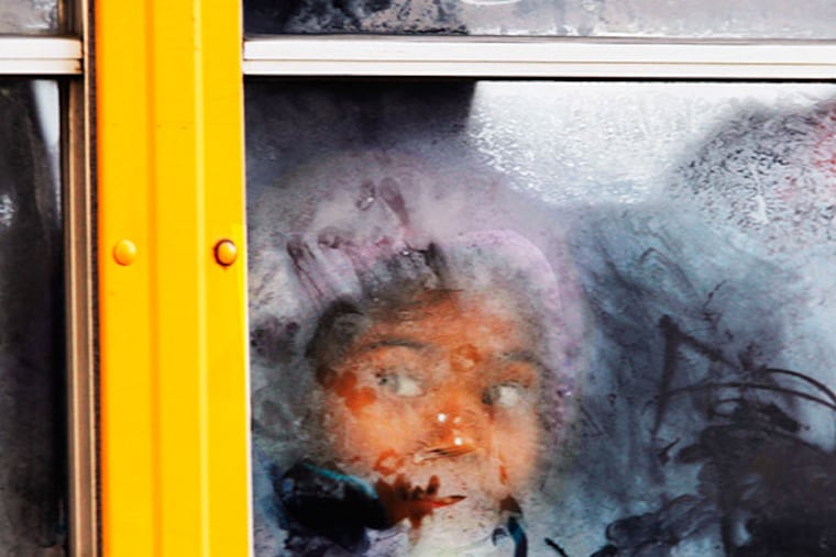 A student looks out the frosted window of a school bus as it moves down 19th Street on Tuesday, January 7, 2014. ( MICHAEL S. WIRTZ / staff photographer )