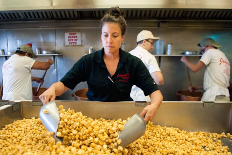 Becky Juzwiak turns the popcorn to spread out the toppings at a Johnson's Popcorn on the Ocean City Boardwalk on Friday, July 3, 2015. (MICHAEL PRONZATO / Staff Photographer)