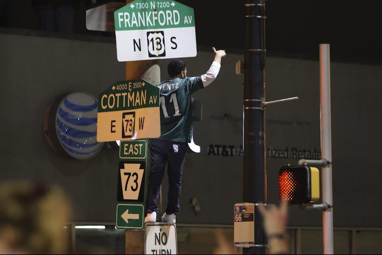 A fan climbs a pole at Cottman and Frankford Avenues in Mayfair following the Eagles’ win over the Minnesota Vikings in the NFC championship game.