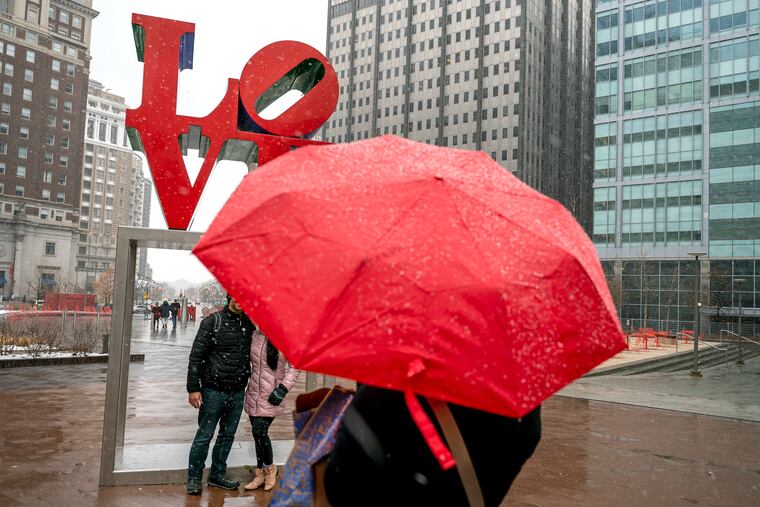 Lovers and tourists pose in front of Robert Indiana’s iconic statue as they visit LOVE Park Feb. 13, 2022 on a snowy pre-Valentine's Day.