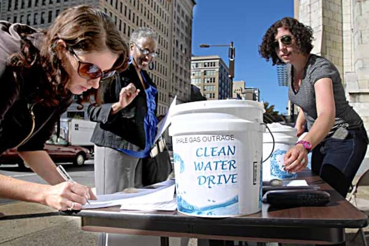 Coryn Wolk, right, of Protecting Our Waters, collects signatures on petitions and hands out some fliers on the Water Drive . The drive began on Sept. 24, 2013 at Broad and Arch Sts. outside the Arch St. United Methodist Church. Groups are collecting water for Pennsylvania residents whose water has been contaminated by gas drilling. ( CHARLES FOX / Staff Photographer )